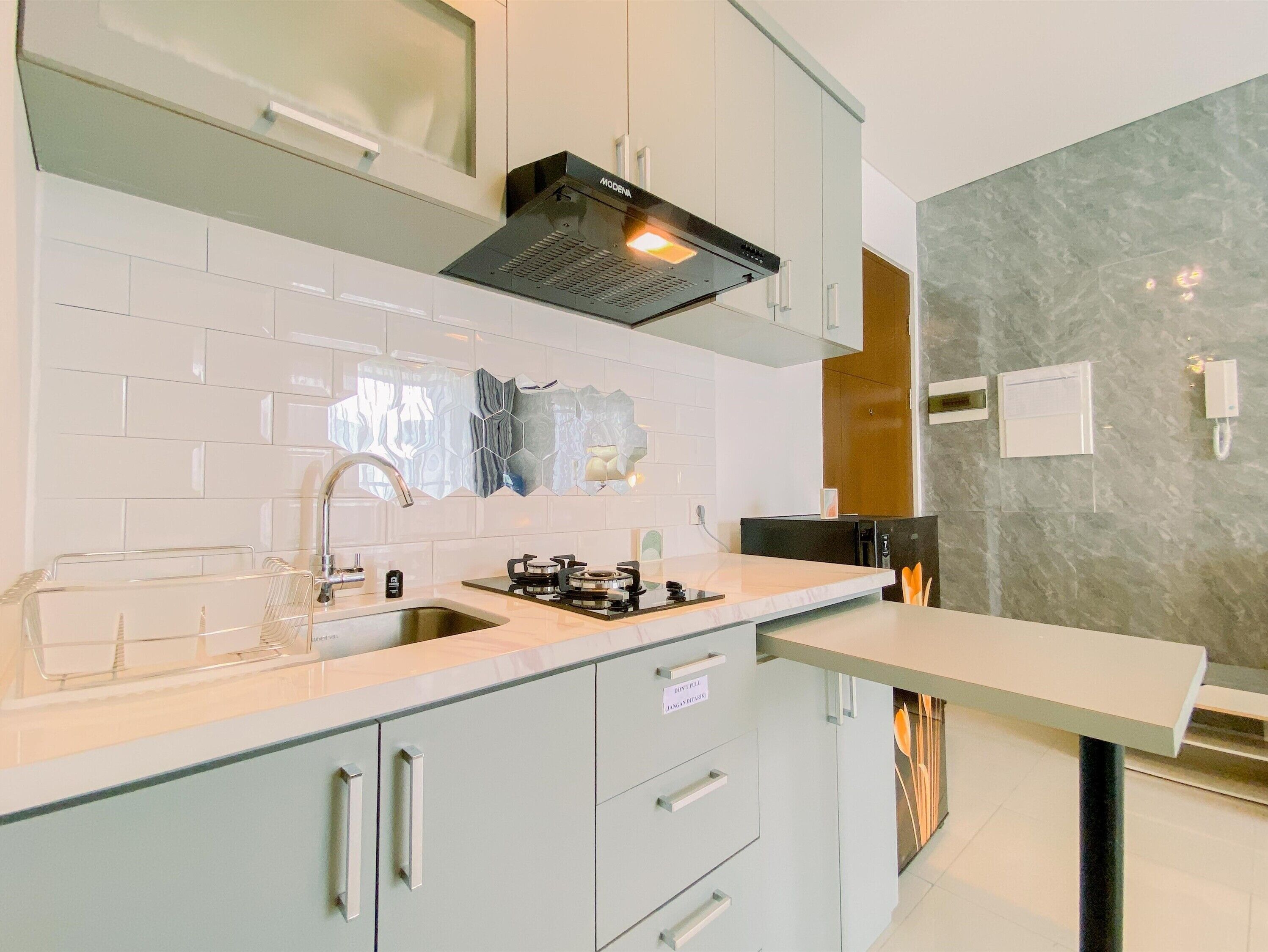 A modern kitchen with white cabinets, a stainless steel sink, and a built-in stove.