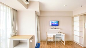 Een hotelkamer met een bureau, stoel, televisie en een kledingkast.