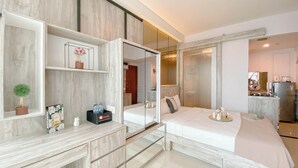 Ein modernes Hotelzimmer mit einem großen Bett, einem Schminktisch mit Spiegel und einer kleinen Küchenzeile.