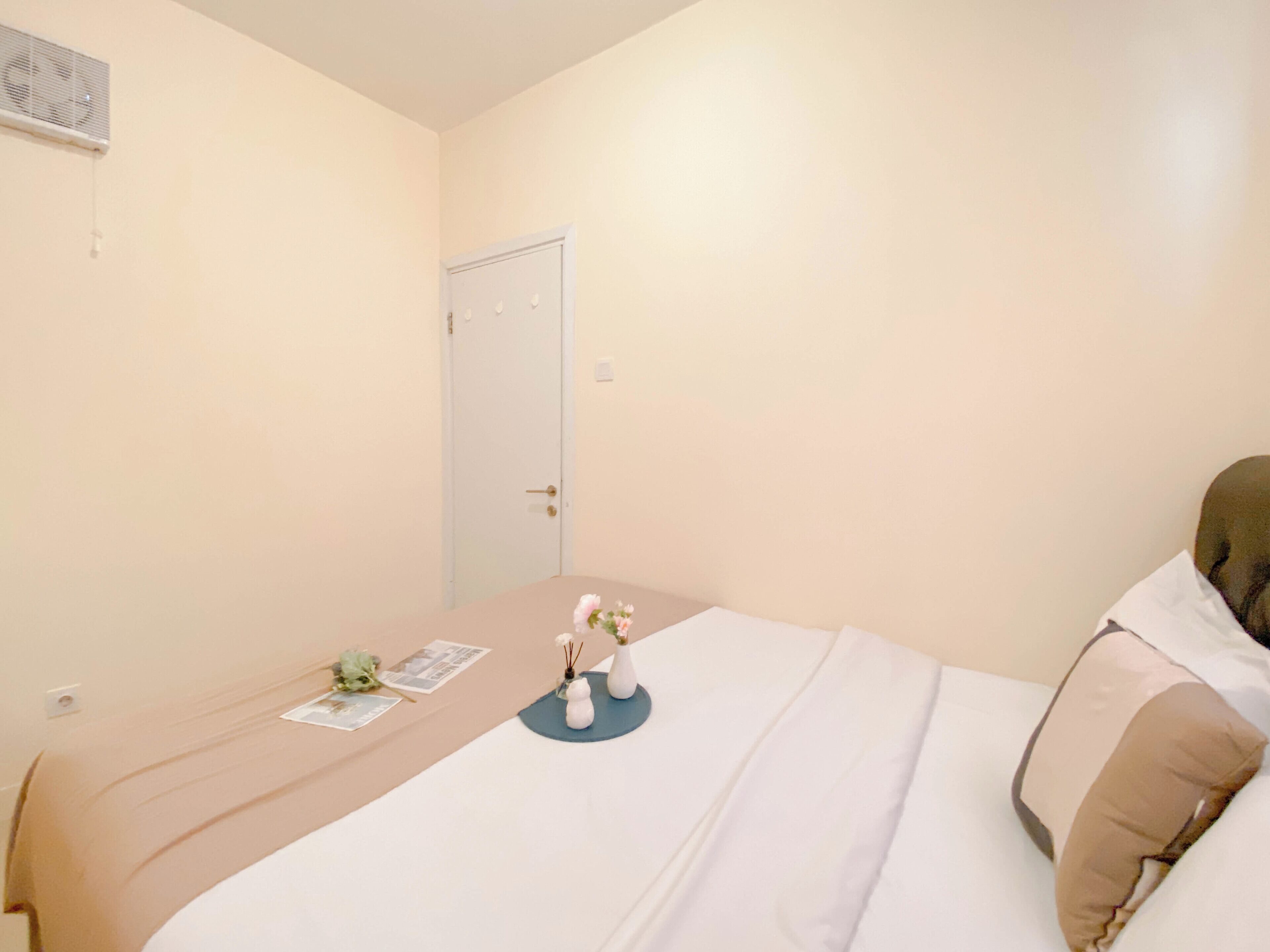 A neatly arranged bedroom with a bed, a bedside table, and a door.