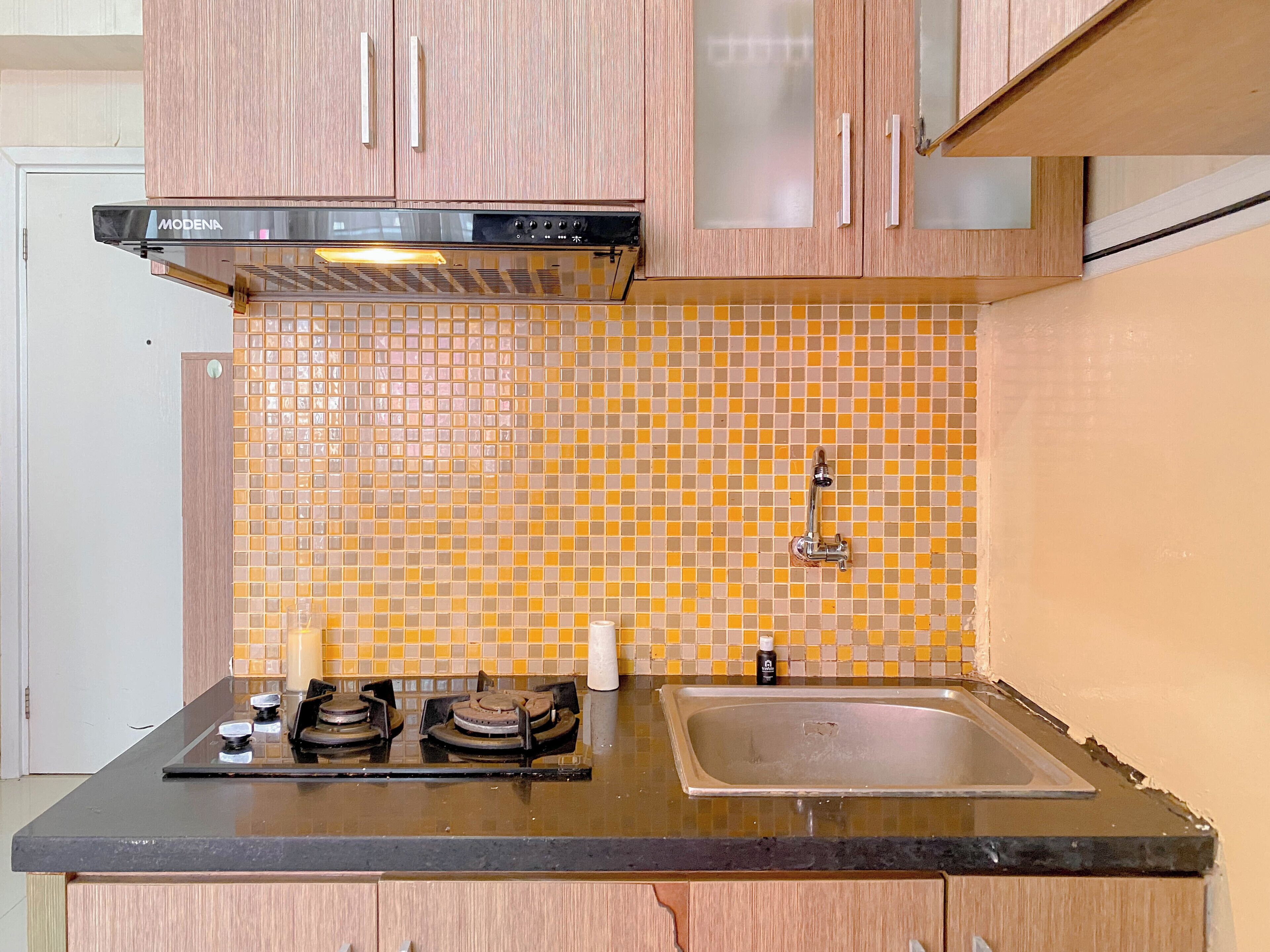 A kitchen with wooden cabinets, a gas stove, a sink, and a tiled backsplash.