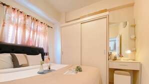 A bedroom with a bed, bedside table, and a dresser with a mirror. - Good and Warm 2BR at Green Pramuka City Apartment (Jakarta)