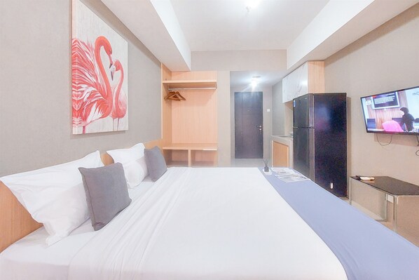 Une chambre d’hôtel avec un grand lit, une télévision, une armoire et un tableau représentant des flamants roses.