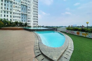 Enjoy a refreshing dip in the rooftop pool surrounded by lush greenery and a city view.