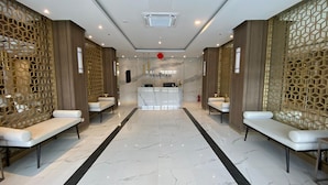A hotel lobby with a reception desk, two seating areas, and a marble floor. - Spacious and Comfort Studio Loft at Kingland Avenue Apartment (South Tangerang)