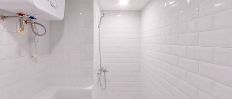 A small, white-tiled bathroom with a shower, a toilet, and a sink.
