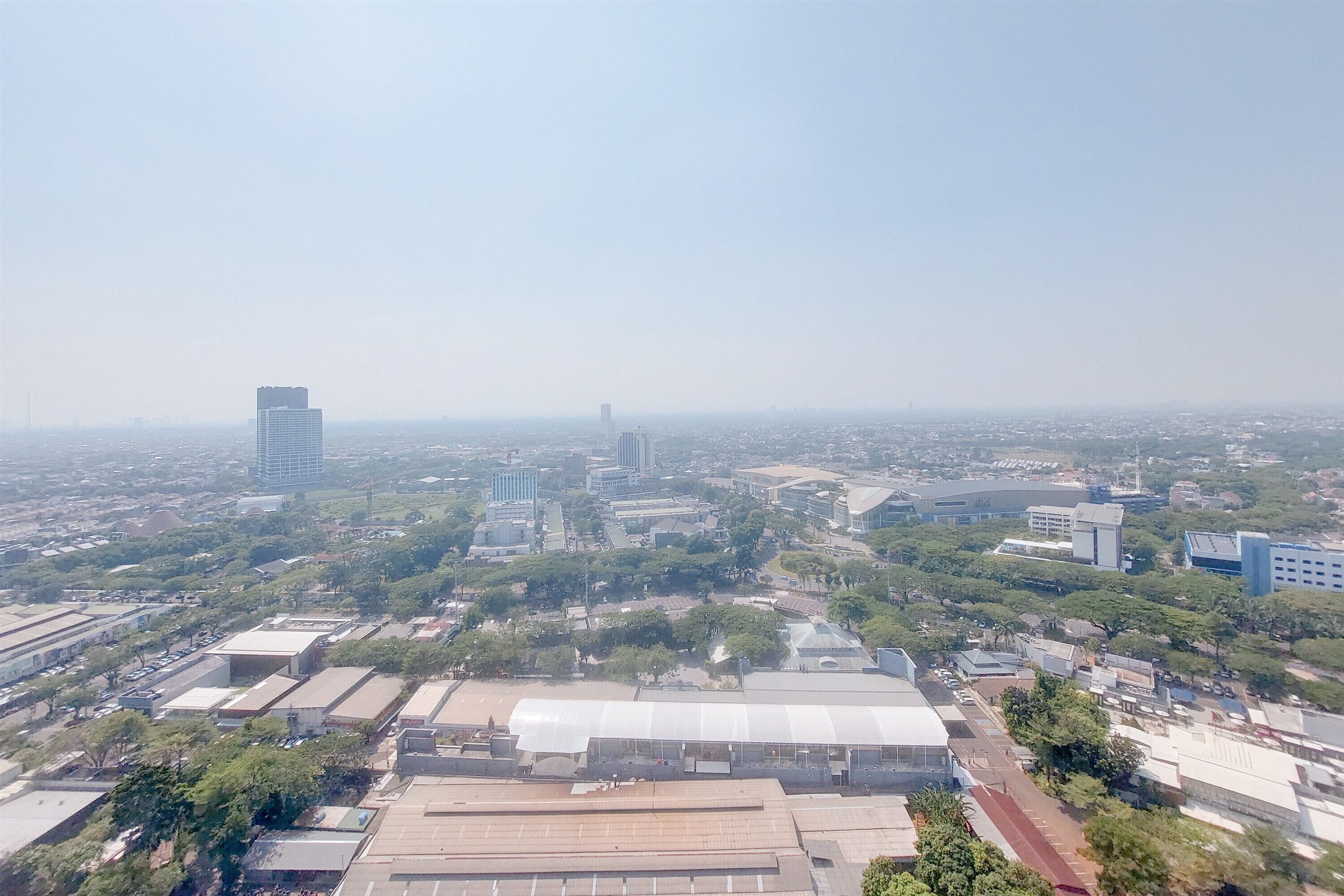 An aerial view of a cityscape with various buildings, including a large covered structure and several high-rise buildings.