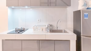 A modern kitchen with a stainless steel refrigerator, a sink, and a countertop with a dish rack and a kettle. - Homey and Comfy Studio Loft at Kingland Avenue Apartment (South Tangerang)