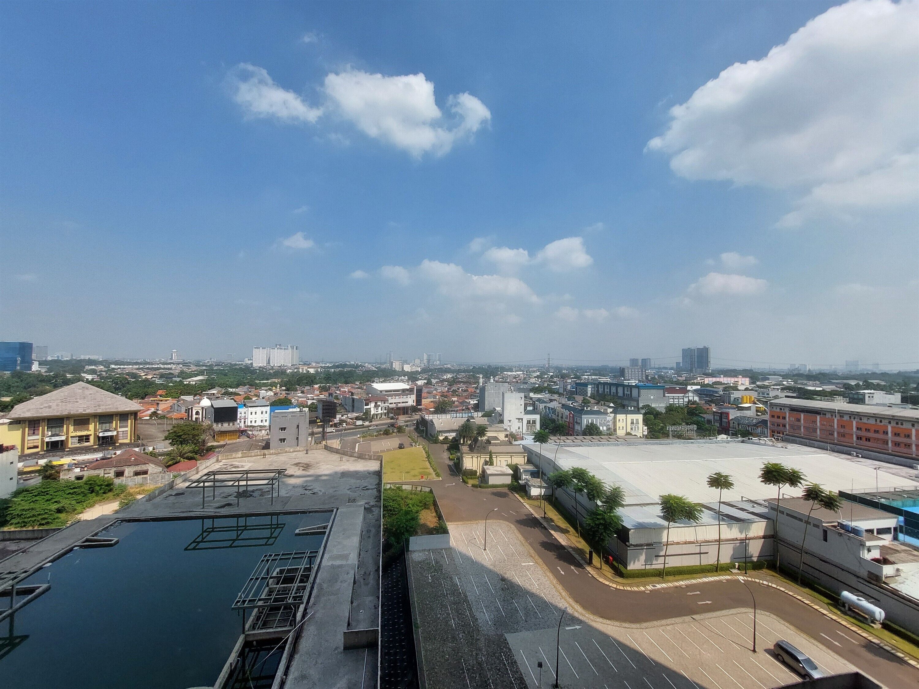 Stadtbild mit großem Parkplatz, Gebäuden und blauem Himmel.