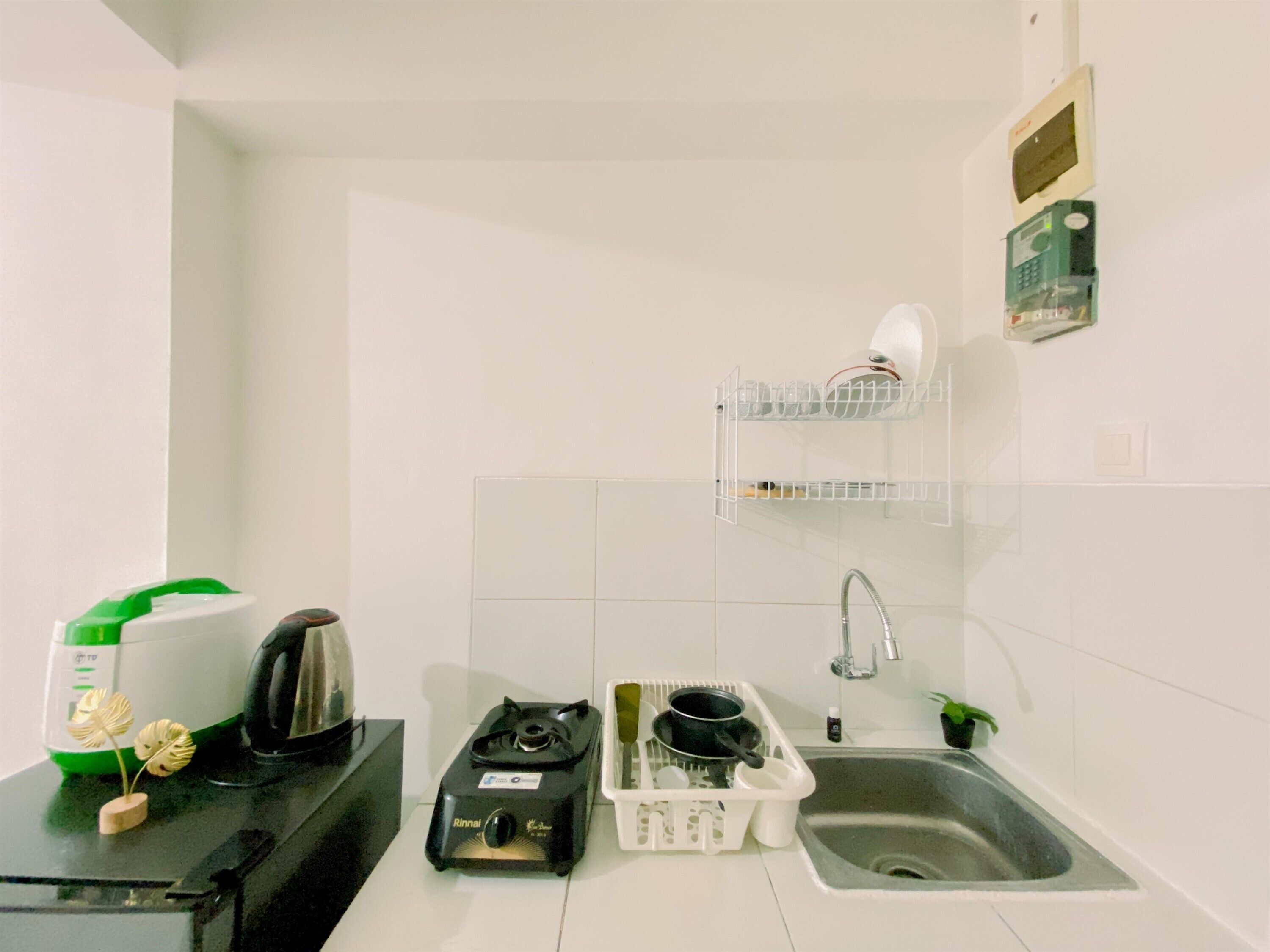 Una pequeña kitchenette con estufa a gas, un lavamanos y un escurreplatos.