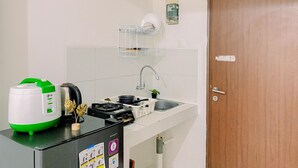 A compact kitchen with a gas stove, a rice cooker, and a small sink.