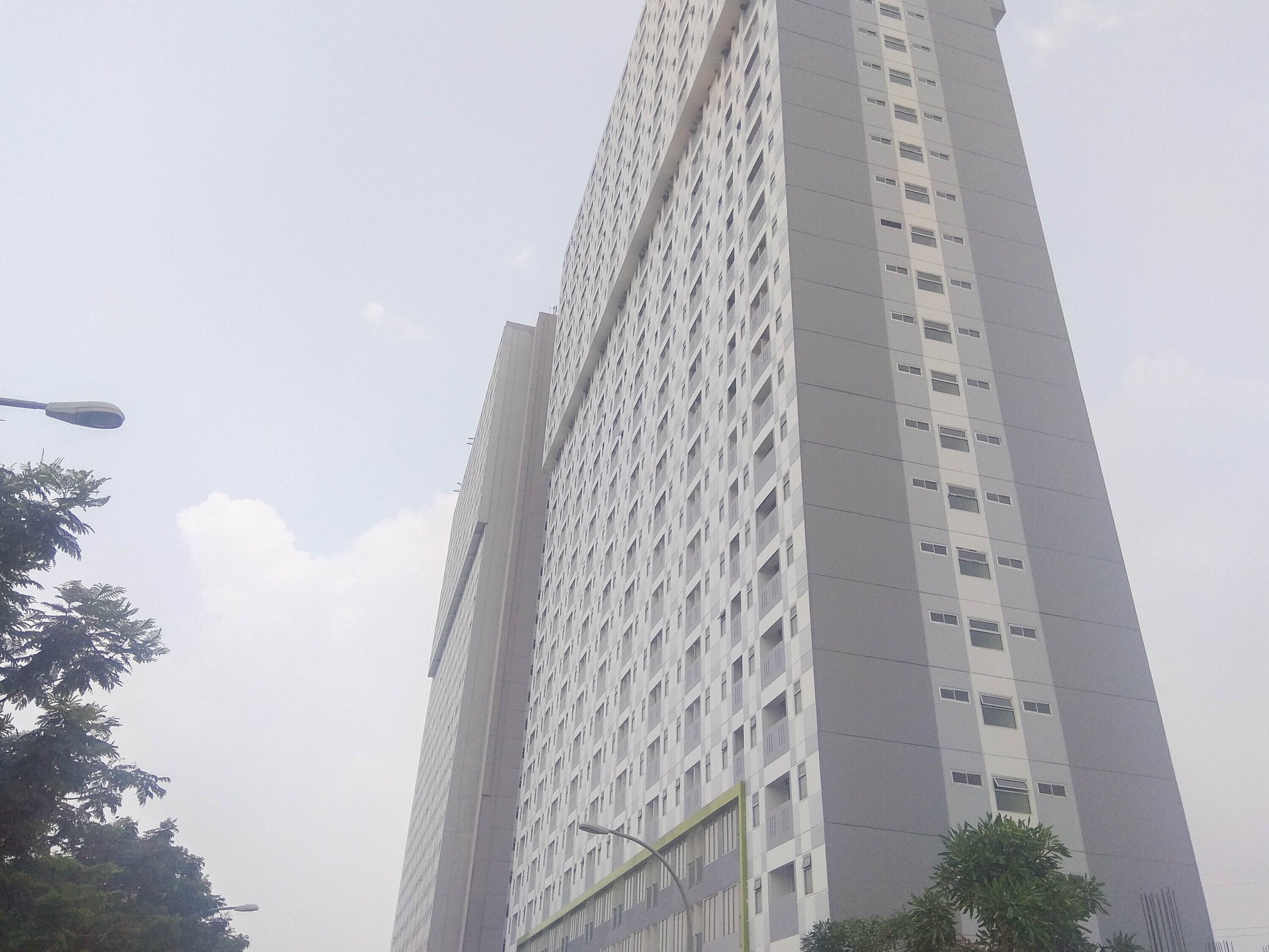 Un edificio alto y moderno con fachada enrejada y ventanas regularmente distribuidas.