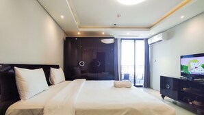 Una camera d'albergo con un letto grande, una televisione e un balcone con mobili da esterno.