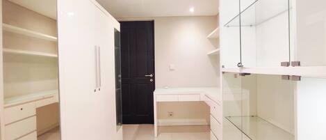 A modern, well-lit room with white cabinetry, a black door, and a glass partition.