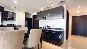 Una cucina moderna con mobili scuri, un'isola centrale e un'area pranzo con sedie.