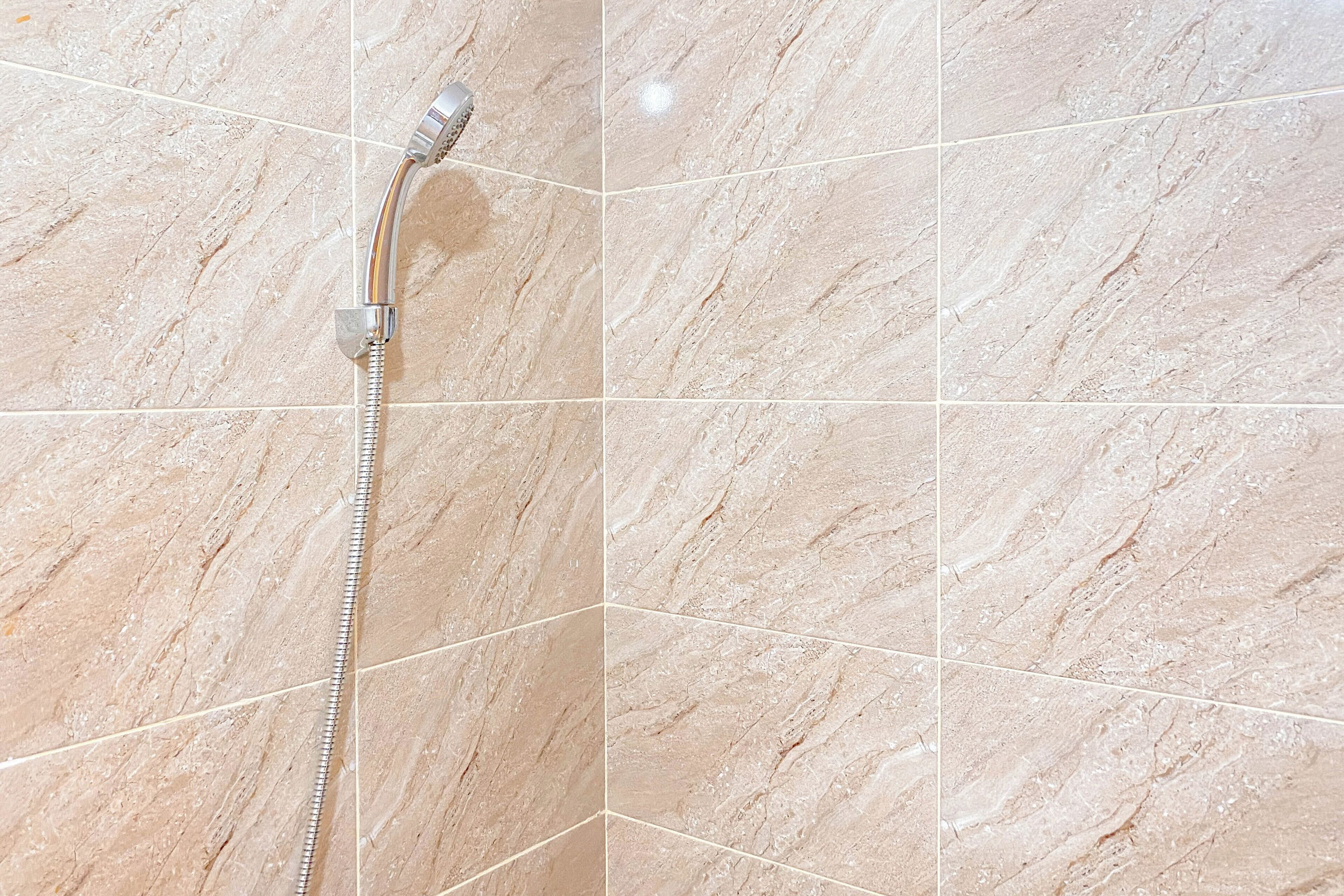 A showerhead attached to a wall with a marble-like tile pattern.