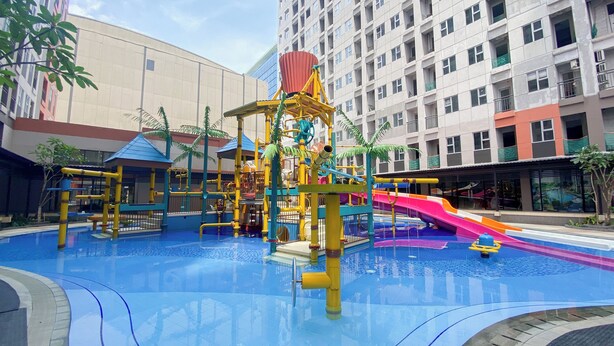 A water park with slides and play structures, surrounded by a building with balconies.