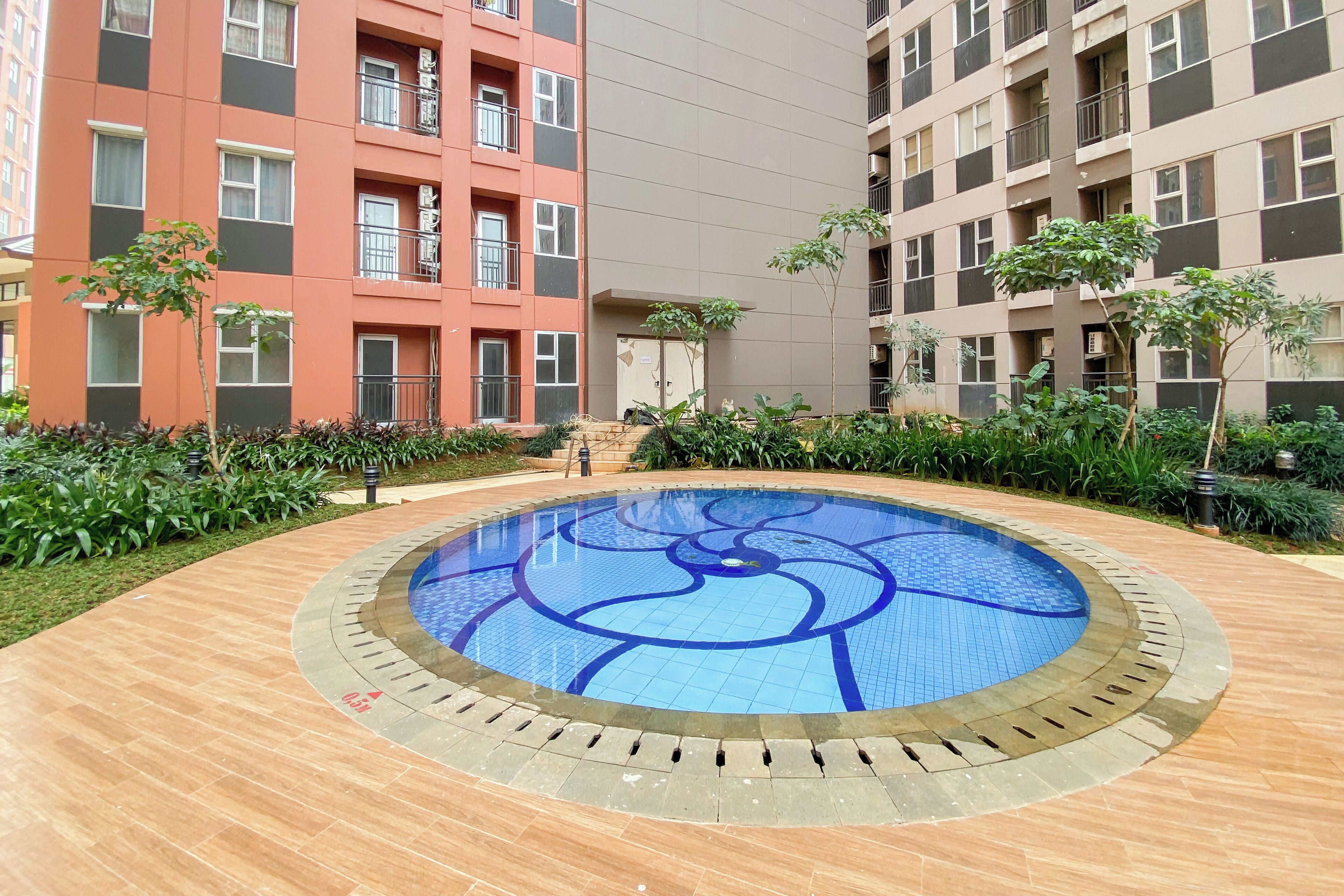 A circular pool with a blue mosaic design, surrounded by a tiled walkway.