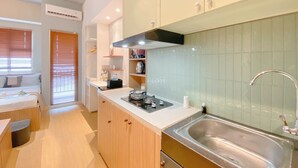 A compact kitchen with a sink, stove, and wooden cabinets.