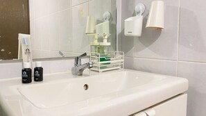 A bathroom with a white sink, a mirror, and toiletries including a toothbrush and two bottles.