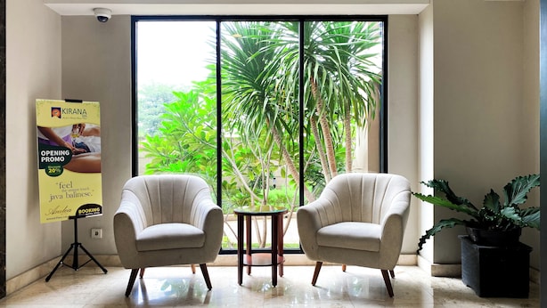 A room with two armchairs, a small table, and a poster on the wall. - Modern Look and Restful Studio at Azalea Suites Apartment (Cikarang)