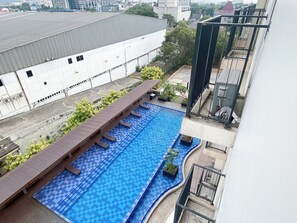 Une piscine sur le toit, dont le fond présente un motif à carreaux, entourée d’une terrasse en bois et agrémentée de plantes en pot.