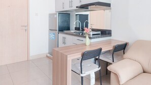 A compact kitchen with a wooden table, two chairs, and a sofa. - Good Choice and Restful 1BR at Tree Park City BSD Apartment (South Tangerang)