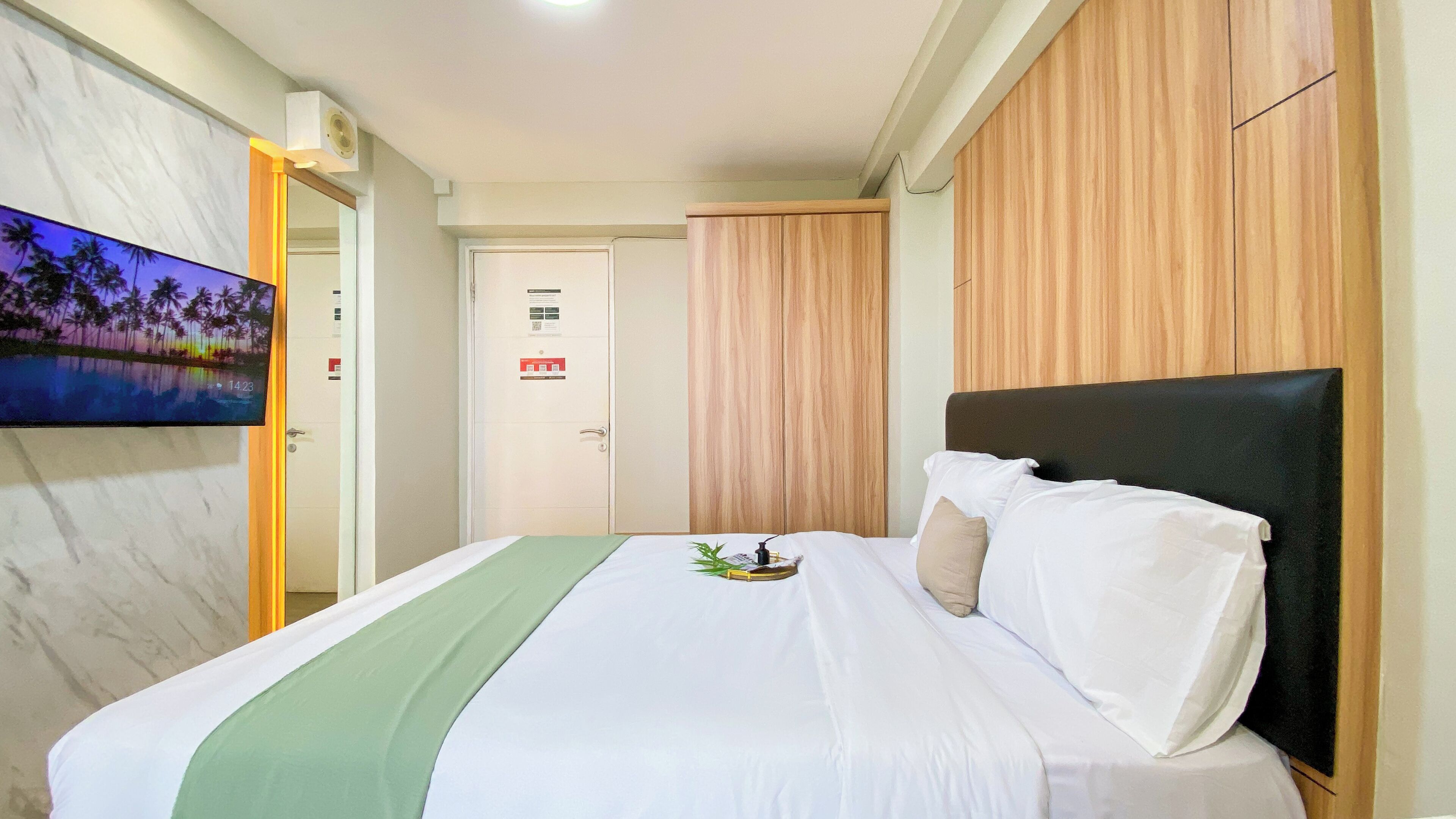 Ein Hotelzimmer mit einem Bett, einem an der Wand befestigten Fernseher und einem Holzschrank.