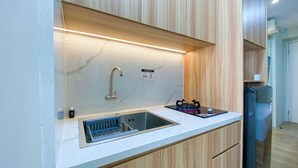 A modern kitchen with a built-in sink, a stainless steel faucet, and a gas stove. - Comfy and Minimalist Studio at Bassura City Apartment (Jakarta)