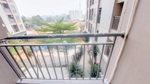 Un balcón con baranda de metal que da a una zona residencial con árboles y edificios.