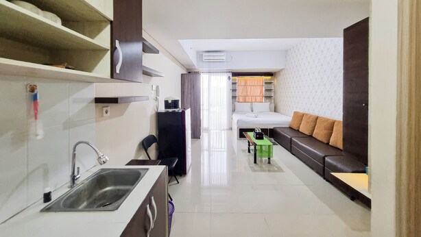 A compact hotel room with a kitchenette, a sofa, a small table, and a bed. - Cozy and Good Place Studio at Taman Melati Sinduadi Apartment (Pogung Lor)