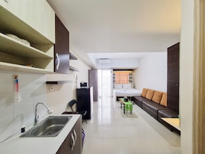 A compact hotel room with a kitchenette, a sofa, a small table, and a bed. - Cozy and Good Place Studio at Taman Melati Sinduadi Apartment (Pogung Lor)