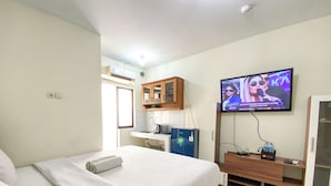 Una camera d'albergo con un letto, una televisione a muro, un angolo cottura e una finestra.