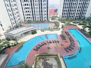 Un edificio residencial con piscina, sillas de descanso y una cancha de baloncesto.