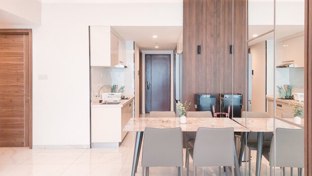 A modern kitchen with a marble countertop, grey chairs, and a wooden door. - Big Spacious and Homey 3BR at Sky House BSD Apartment (Pagedangan)