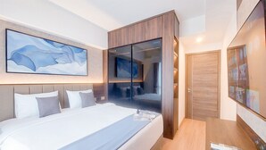 A modern hotel room with a large bed, a desk, and a wardrobe. - Big Spacious and Homey 3BR at Sky House BSD Apartment (Pagedangan)
