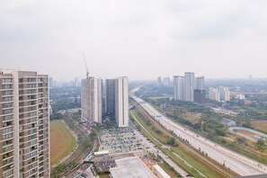 Un edificio de gran altura con varios pisos, rodeado de otros edificios altos y una autopista.