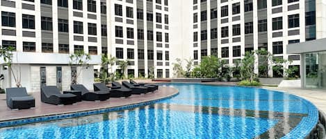 A modern hotel with a large indoor swimming pool surrounded by lounge chairs and greenery.