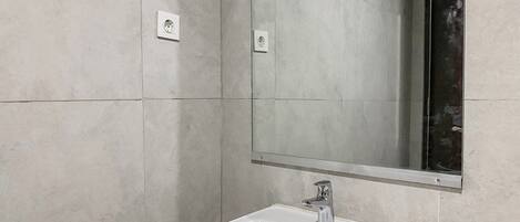 A bathroom with a white sink, a mirror, and a window.