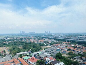 A residential area with houses, some with red roofs, and a highway in the background. - Simply Look and Restful Studio Pollux Chadstone Apartment (Cikarang)