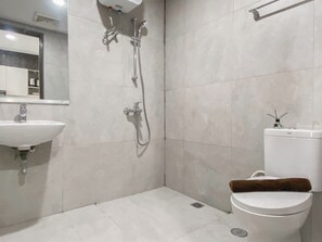 A modern bathroom with a white sink, a toilet, and a shower with a handheld showerhead. - Simply Look and Restful Studio Pollux Chadstone Apartment (Cikarang)