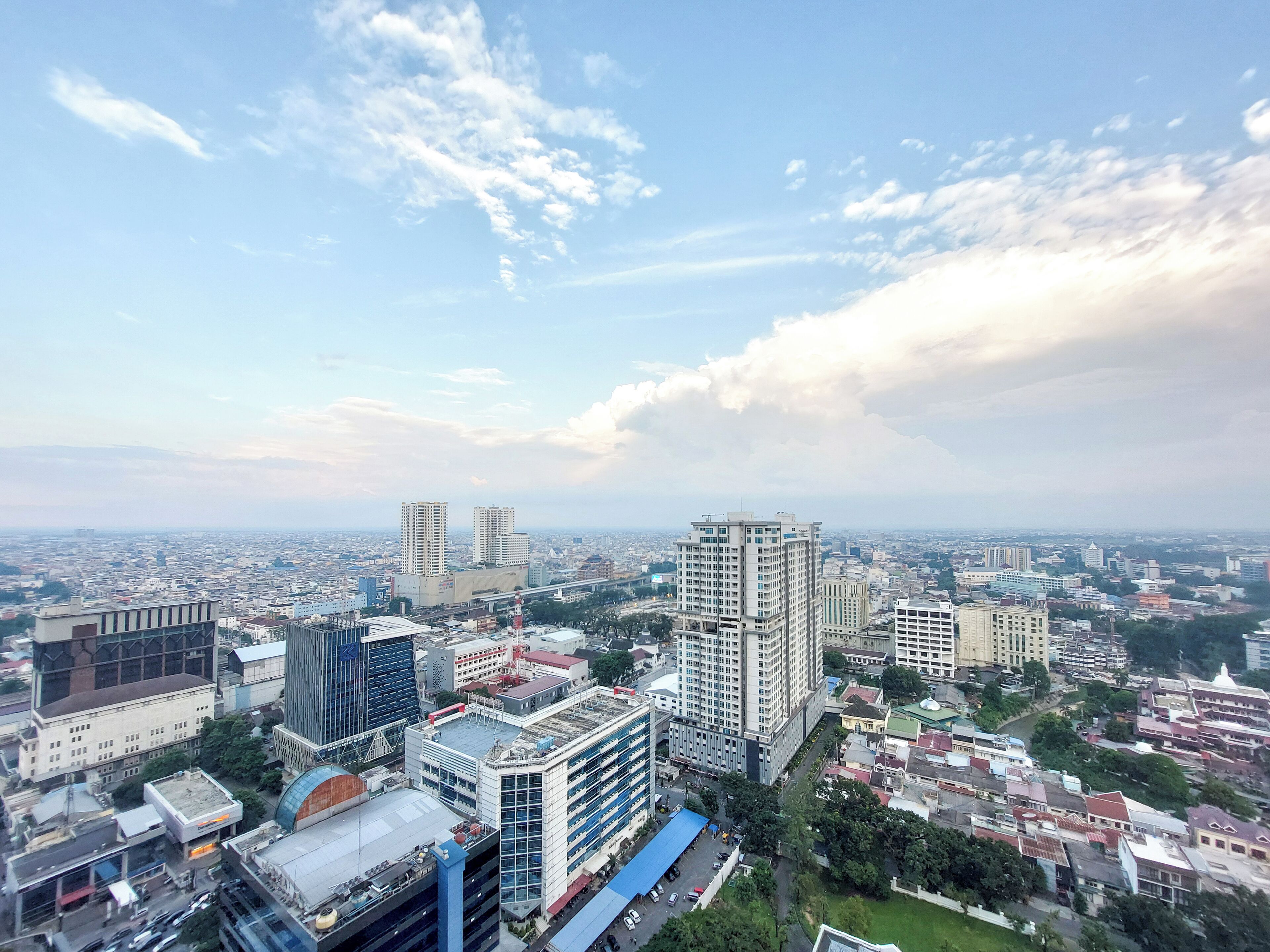 A cityscape with high-rise buildings, a mix of modern and older architecture, and a clear sky with scattered clouds.