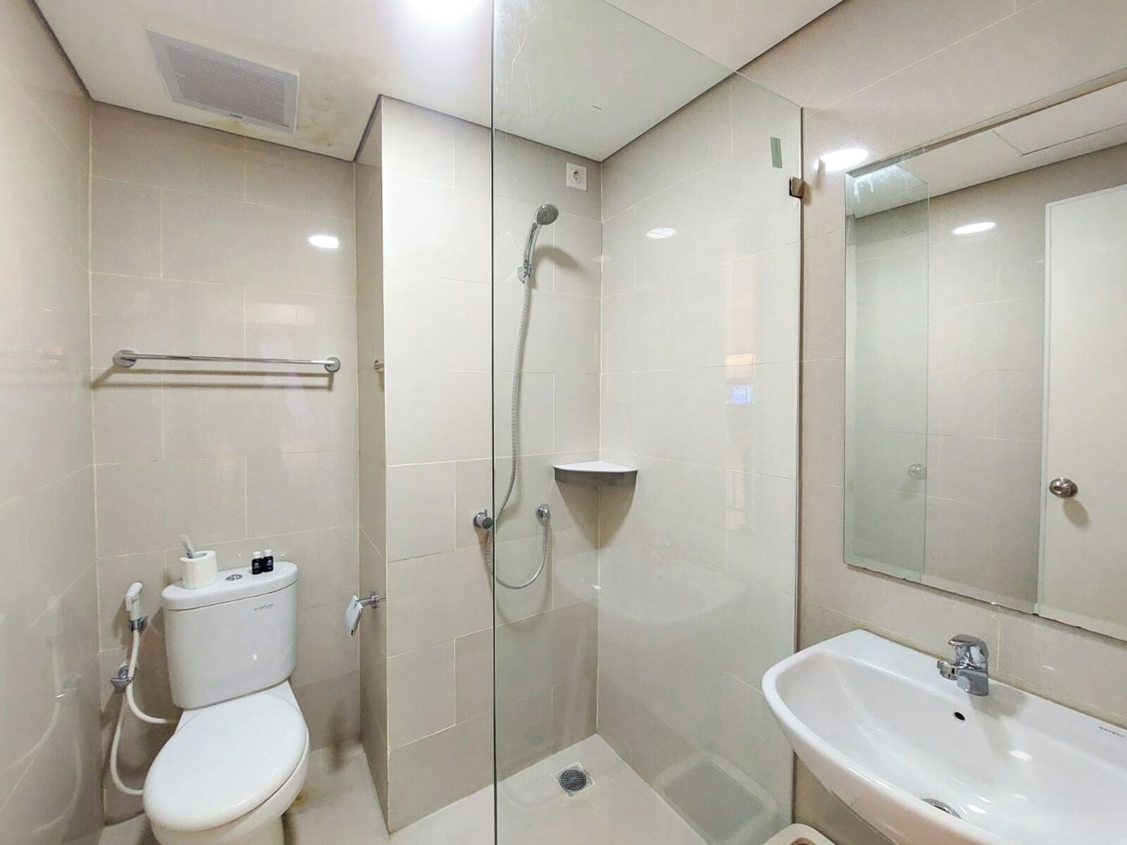 Une salle de bain moderne avec une douche à parois de verre, des toilettes et un lavabo avec un miroir.
