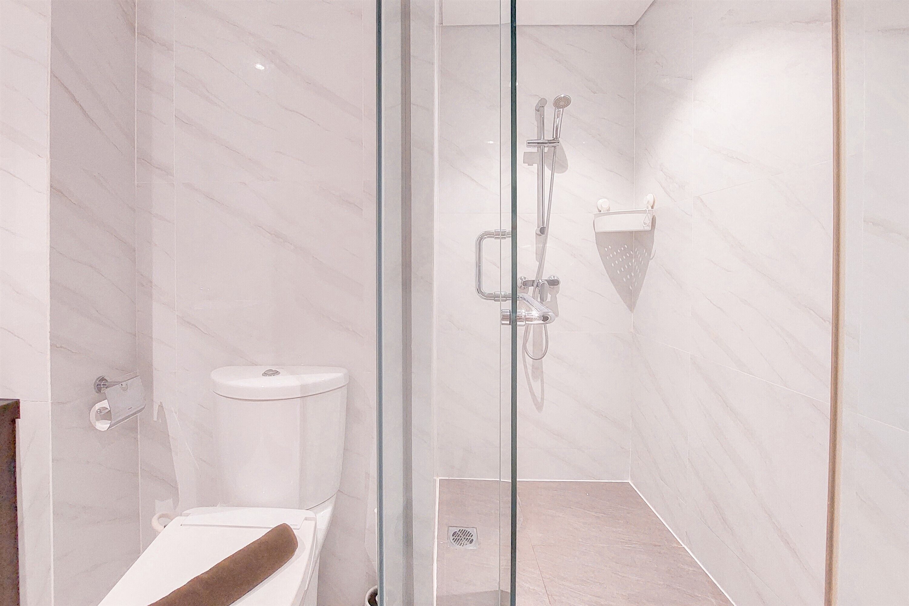 A modern bathroom with a glass shower enclosure, a toilet, and a towel rack.