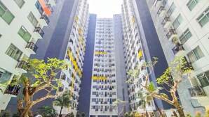 Un edificio residencial alto con múltiples balcones, rodeado de vegetación.