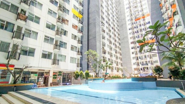 Edificio residencial con varios balcones, piscina y vegetación circundante.