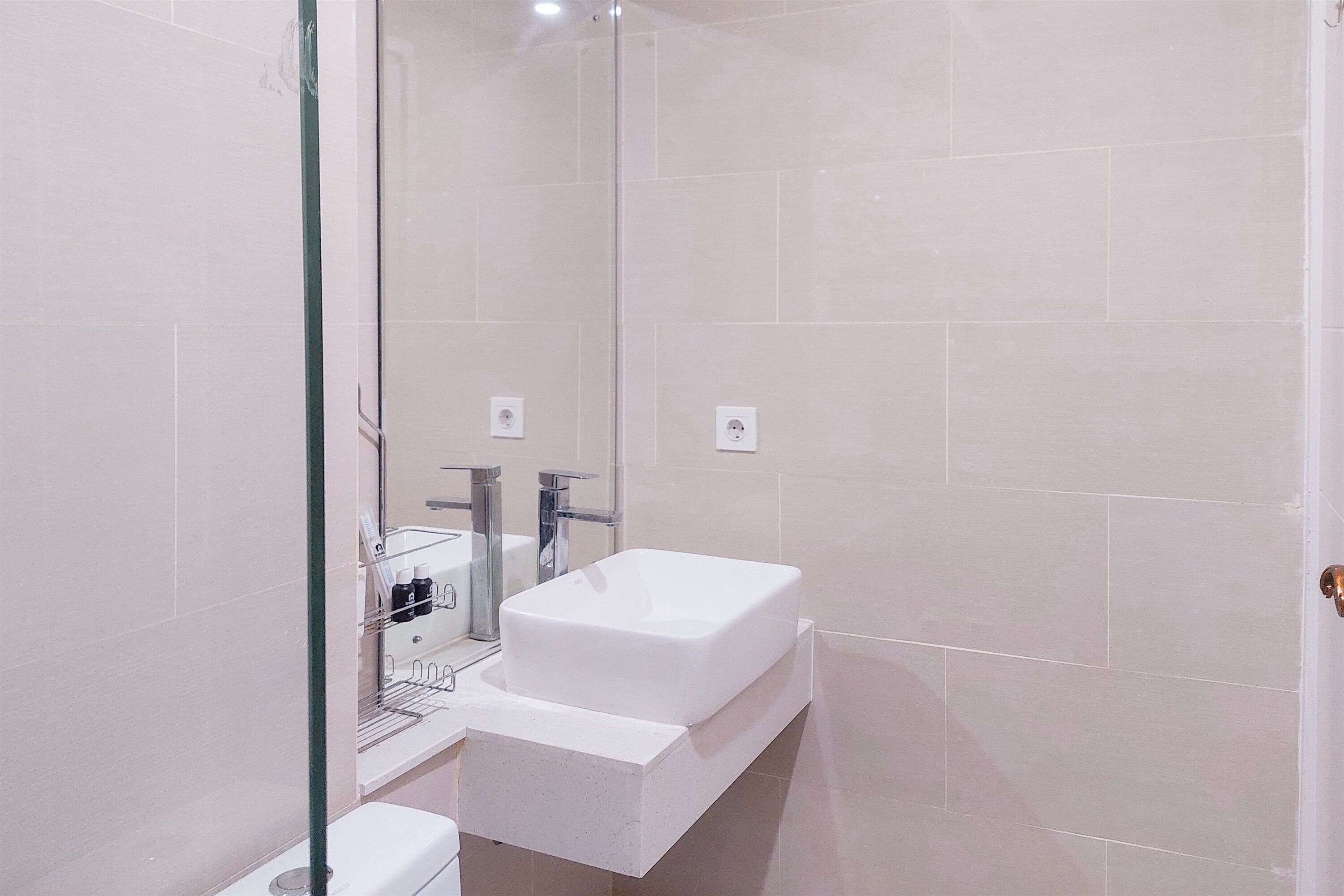 A modern bathroom with a white sink, a glass shower enclosure, and a mirror.