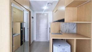 A modern kitchen with wooden cabinets, a marble backsplash, and a built-in dishwasher. - Cozy Living Studio at Taman Melati Sinduadi Apartment (Pogung Lor)