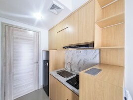 Una cocina compacta con armarios de madera, estufa integrada y encimera de mármol.