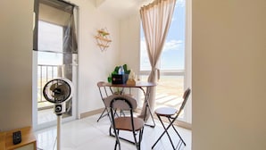 Un balcon avec une table, des chaises, un ventilateur et une vue sur la plage.